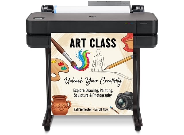 Teacher using a poster making machine to print a large colorful classroom poster on wide-format paper.